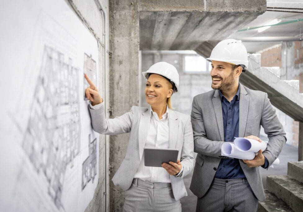 Civil engineers working together at construction site, controlling and inspecting building process. Looking at project plan and blueprint.